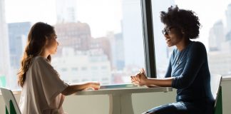 Two Women Sitting on Chairs Beside Window