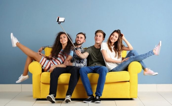Friends sitting on a yellow couch taking a selfie Friends sitting on a yellow couch taking a selfie