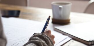 A person writing on a piece of paper Description automatically generated with medium confidence