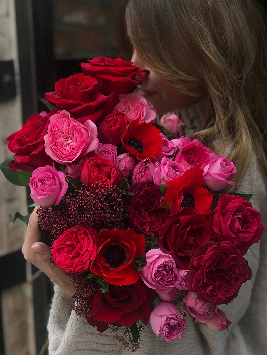 A person holding a bouquet of red roses
Description automatically generated