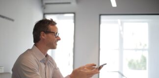 Smiling adult businessman at table with gadgets holding presentation