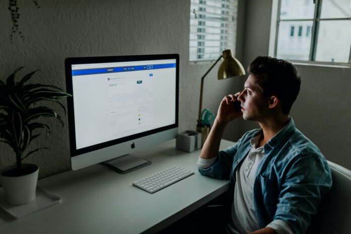 Photo by Austin Distel man in blue denim jacket facing turned on monitor