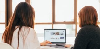two women talking while looking at laptop computer