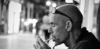 grayscale photo of man lighting cigarette