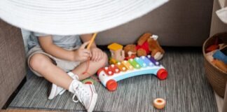 child sitting on floor and playing with xylophone toy
