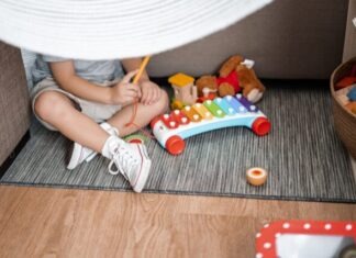 5 Reasons to Buy Cubby House for Your Child child sitting on floor and playing with xylophone toy