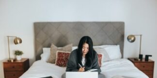 woman in black hijab sitting on bed using laptop