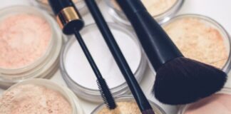 three makeup brushes on top of compact powders