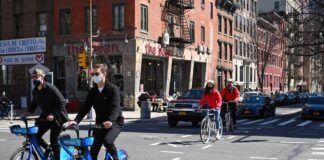 man in black jacket riding blue bicycle on street during daytime