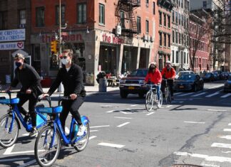 E-Bikes Are Good For The Environment man in black jacket riding blue bicycle on street during daytime