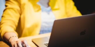 person in yellow dress shirt using black laptop computer