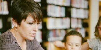 woman in gray long sleeve shirt sitting beside boy in orange crew neck shirt