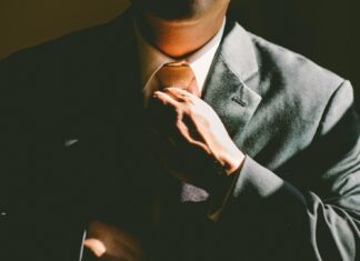 Is it Time to Say Good-Bye to 9-5 Work Week? A man in a black suit loosening his tie