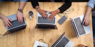 person using macbook pro on brown wooden table