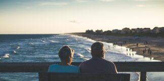 man and woman sitting on bench in front of beach