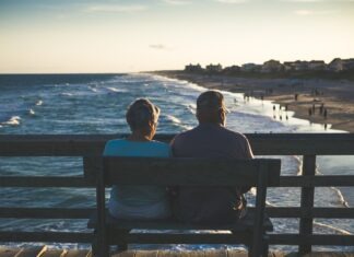 man and woman sitting on bench in front of beach