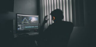 shallow focus photography of man listing to music in front of the computer