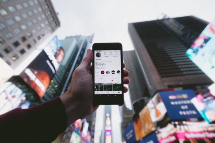 Photo by Jakob Owens high angle photo of person holding turned on smartphone with tall buildings background