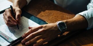 person writing on paper leaning on brown table