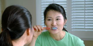 woman in green crew neck shirt holding red lollipop