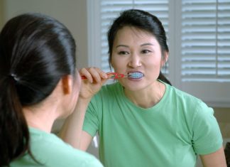 woman in green crew neck shirt holding red lollipop