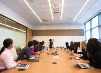 6 Ideas How to Automate your Business With the Help of a Software Development Company people on conference table looking at talking woman