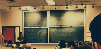 student sitting on chairs in front of chalkboard