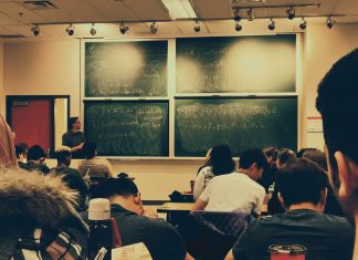 student sitting on chairs in front of chalkboard
