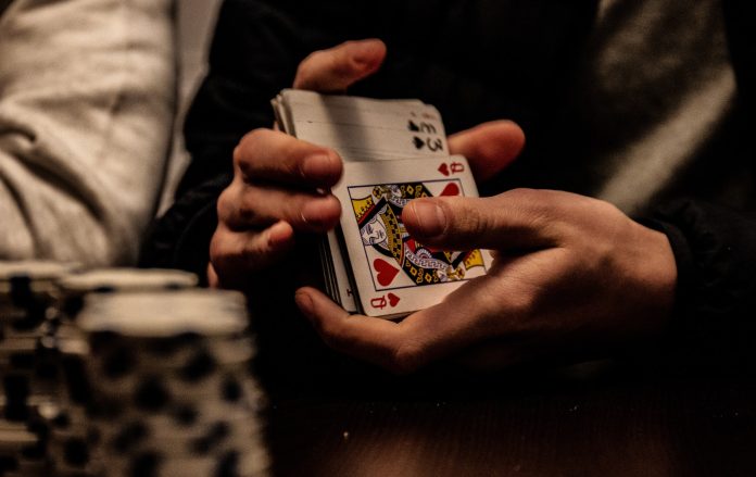 Photo by Marin Tulard person holding king of spade playing card