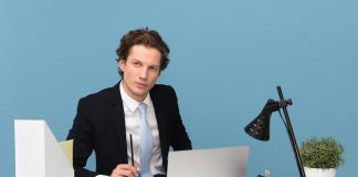 man sitting on chair beside laptop computer and teacup