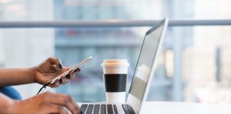 person using smartphone and MacBook