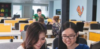 selective focus photography of two women in front of computer monitor