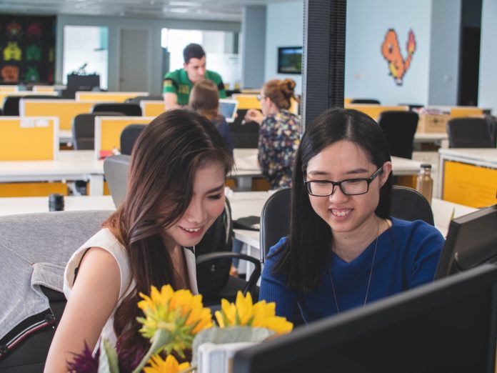 Photo by Mimi Thian selective focus photography of two women in front of computer monitor