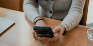 woman in white sweater holding black smartphone