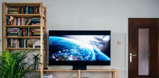 black flat screen tv turned on near brown wooden shelf