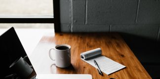 MacBook Pro, white ceramic mug,and black smartphone on table