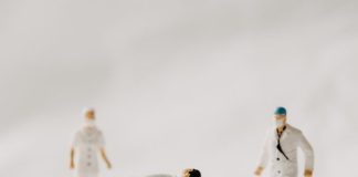 man in white coat and black pants standing beside white wooden picnic table