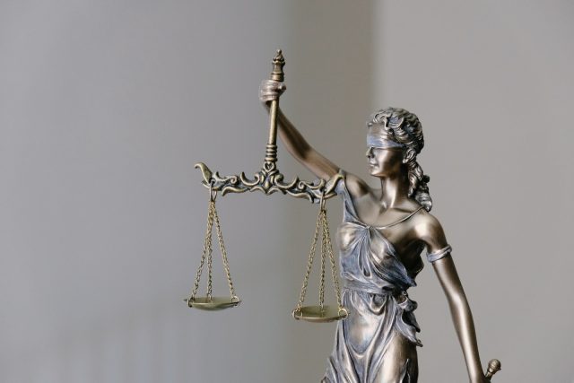 Photo by Tingey Injury Law Firm woman in dress holding sword figurine