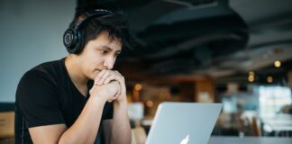 man wearing headphones while sitting on chair in front of MacBook