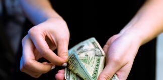 person holding fan of 100 us dollar bill