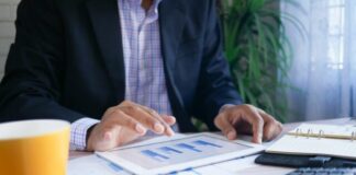 person in black suit jacket holding white tablet computer