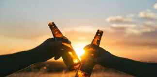 photography of person holding glass bottles during sunset