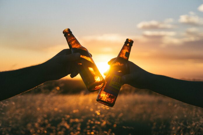 Photo by Wil Stewart photography of person holding glass bottles during sunset