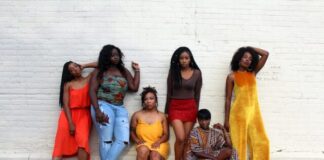 six women leaning on white wall
