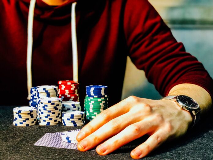 Photo by Chris Liverani person holding playing cards beside poker chips