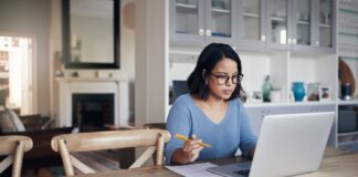 A person sitting at a table with a computer and a pen Description automatically generated with low confidence