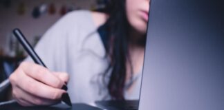 woman using drawing pad while sitting in front of laptop