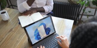 Overhead view of two people at a table working with a Microsoft laptop and notebook