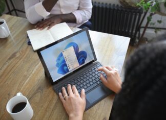 Guide: Undertaking A G Suite to Office 365 Migration Overhead view of two people at a table working with a Microsoft laptop and notebook