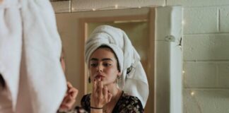woman putting makeup in front of mirror